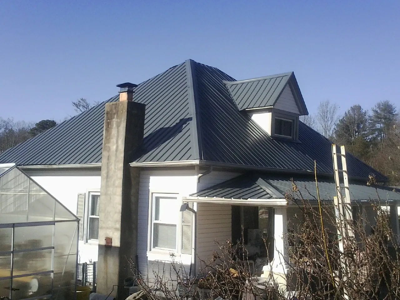 Dark blue standing seam metal roof on a white farmhouse with dormer — Slate & Tile Roof Repair by Roofing Brothers in Glen Gardner