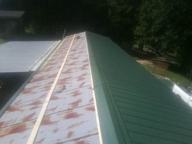 Old rusted panels beside newly installed green metal roofing — Wind Damage Roof Repair by Roofing Brothers in Glen Gardner