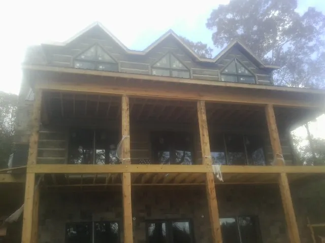 Dormers and porch framing on a large log home under construction — Roof Coating work by our crew in Glen Gardner