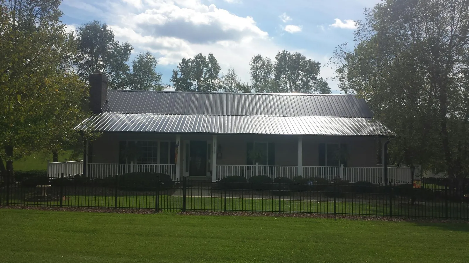 Gray metal roof on a brick ranch with a full width front porch — Gutter Guard Installation work by our crew in Glen Gardner