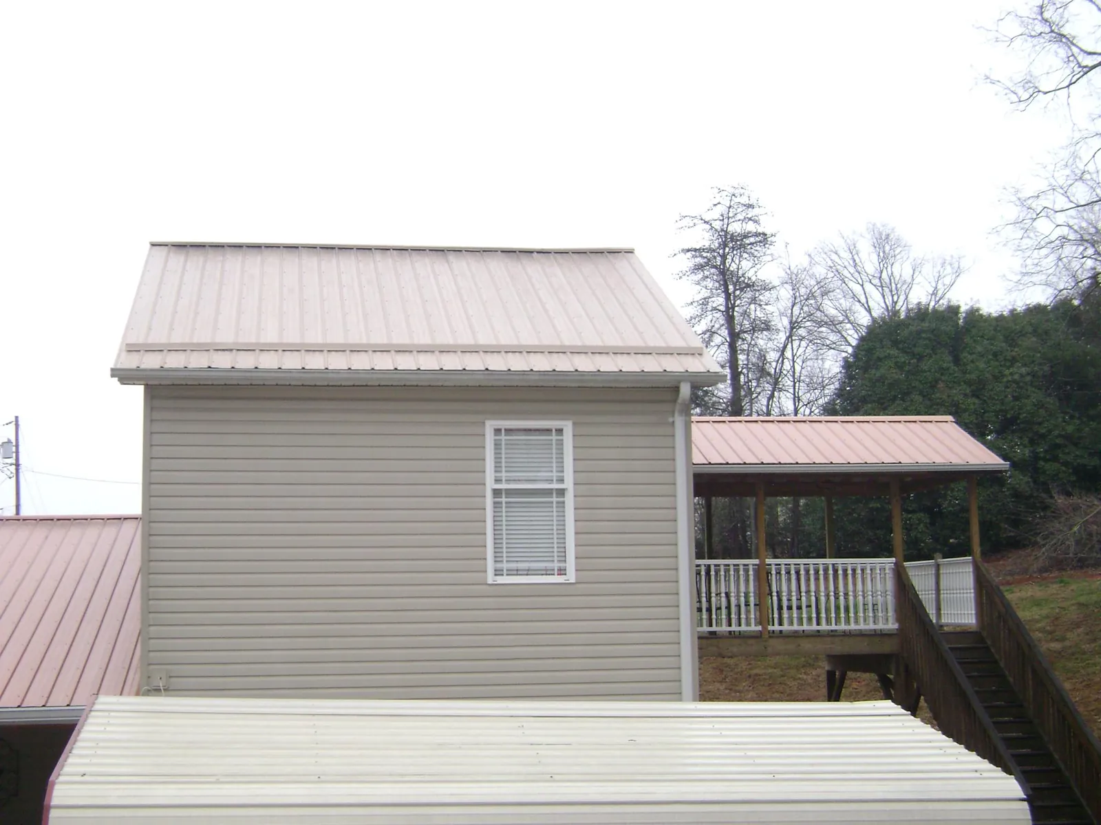 Tan metal roofs on a two story addition and attached porch, from a Roof Replacement job in Glen Gardner