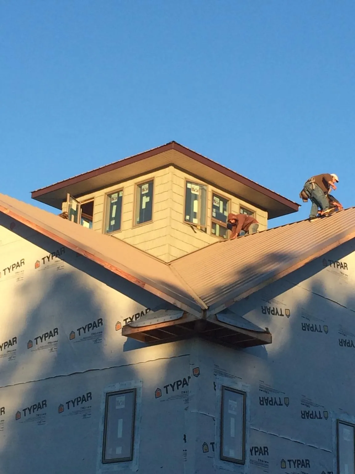 Roofers working around a rooftop cupola on a new metal roof at sunset — Roof Waterproofing in Glen Gardner by Roofing Brothers